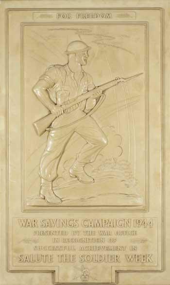 'Salute the Soldier Week' plaque with relief image of a soldier with a gun with fixed bayonet. These plaques were given as rewards to local councils by the War Office during World War Two for successful fundraising efforts. 
