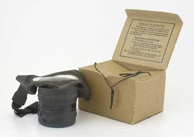 World War Two civilian gasmask. Marked “medium”. Displayed with cardboard carrying case labelled “Mary Berry - 1 Court Orchard”.