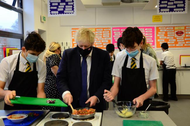 On tour: Boris Johnson helps students prepare a meal at Oak Wood School