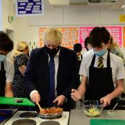 On tour: Boris Johnson helps students prepare a meal at Oak Wood School